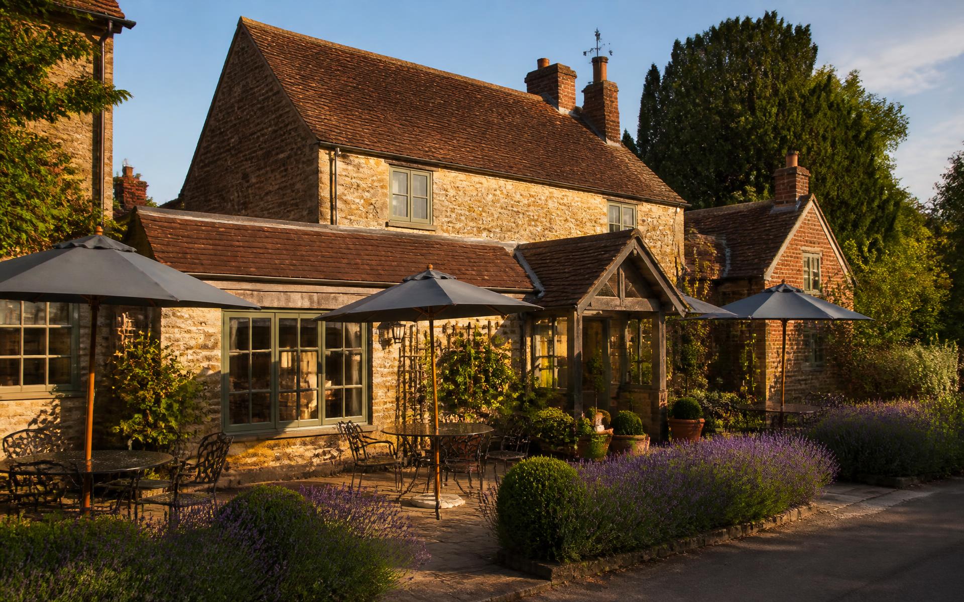 The Mole Inn's honey-stone frontage with lavender borders and parasol tables